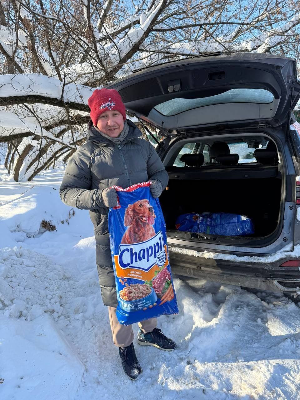 Волонтёр с мешком корма у машины